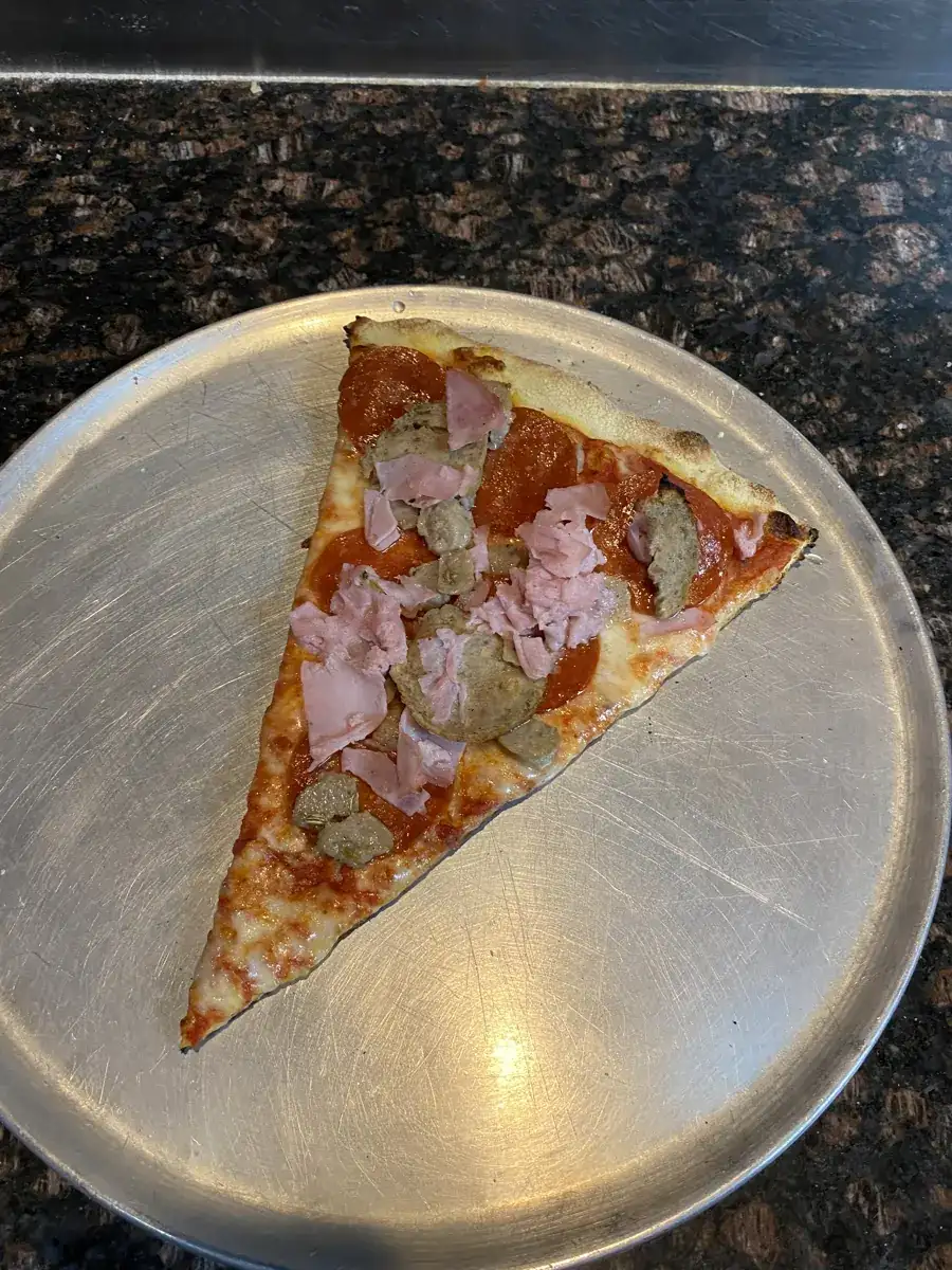 Meat Lovers New York-style slice on a metal pizza tray