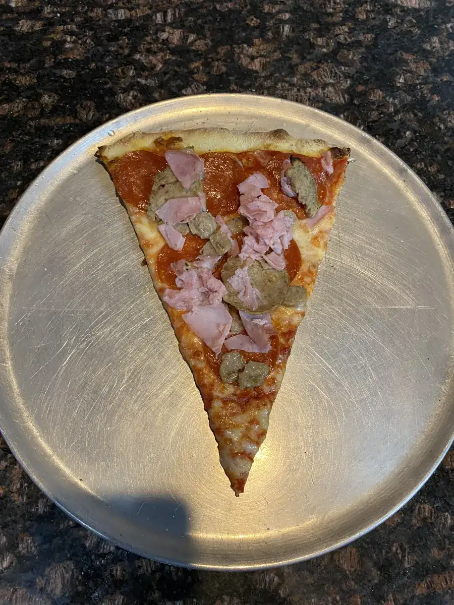Meat Lovers New York-style slice on a metal pizza tray