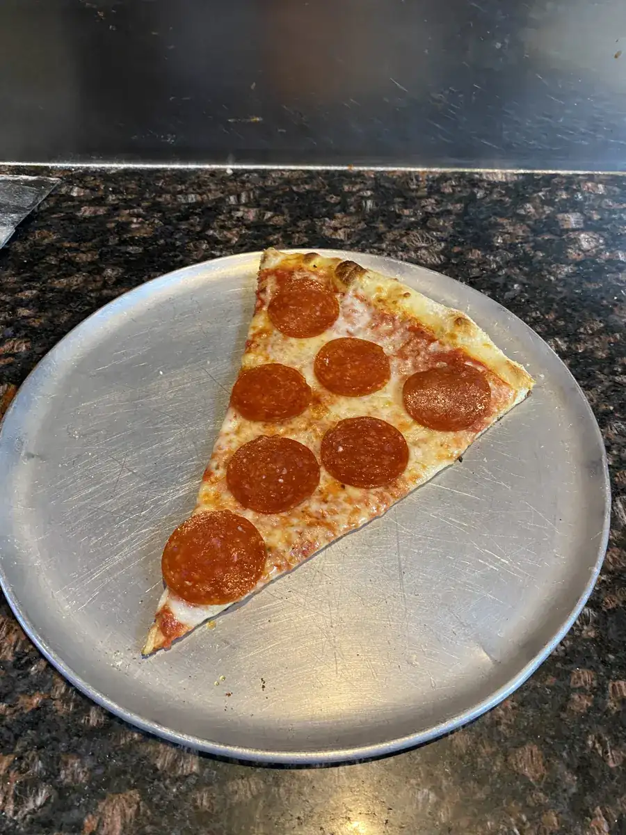 Pepperoni New York-style slice on a metal pizza tray