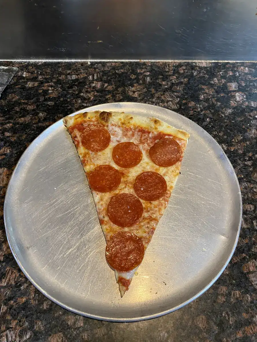 Pepperoni New York-style slice on a metal pizza tray